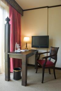 a room with a desk and a chair and a television at Lindner Park-Hotel Hagenbeck in Hamburg