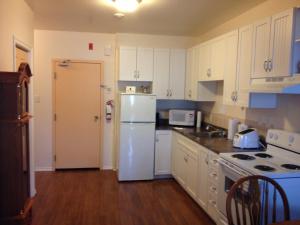 a kitchen with white cabinets and a white refrigerator at Ashton Apartments in St. John's