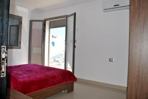 a room with a red bed and a door with a window at Residence La Perle in Triffa