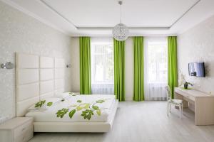 Schlafzimmer mit einem weißen Bett und grünen Vorhängen in der Unterkunft Crystal Apartments in Lwiw
