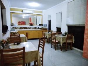 a dining room with tables and chairs and a kitchen at Hotel Marfim I in Sumaré