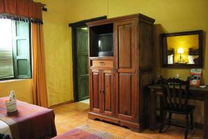 a bedroom with a tv and a wooden cabinet at La Posada de Suchitlan in Suchitoto