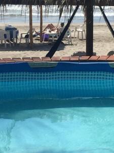 
a beach with a pool and a blue chair at Casa de las Olas Surf & Beach Club in Acapulco
