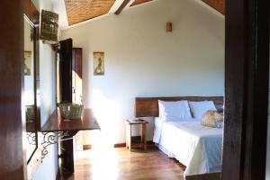 a bedroom with a white bed and a wooden floor at Chale Vista Encantada in Lavras Novas