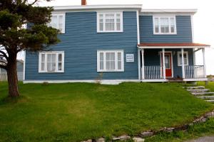 a blue house with a red door on a green yard at Kelly's Landing in Trinity