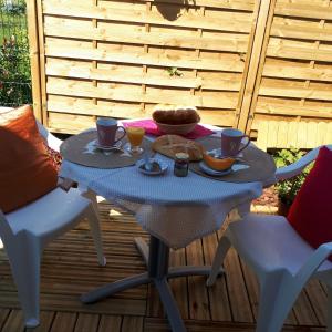 a table with two chairs and a table with food on it at La salamandre, Chambre d'hôtes in Étaules