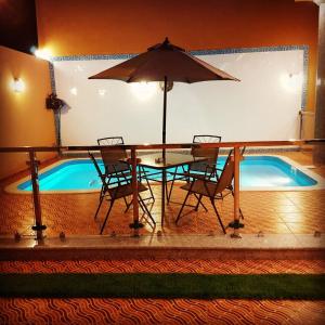 a table with chairs and an umbrella next to a swimming pool at Abo Naif Resort in Rayyis