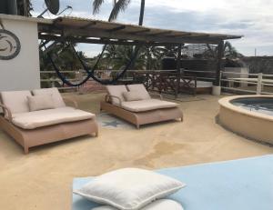
a lounge area with chairs, tables and umbrellas at Casa de las Olas Surf & Beach Club in Acapulco
