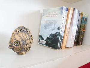 ein Buch und ein Fisch auf einem Regal mit Büchern in der Unterkunft Haus Diana *Ferienwohnung Wattenmeer* in Wittdün + 12 Fotos