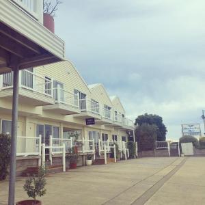 A Great Ocean View Motel في خليج أبولو: صف من البيوت عليها شرفات بيضاء