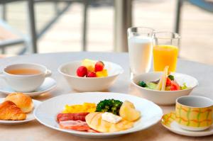 a table with plates of breakfast foods and cups of orange juice at Grand Prince Hotel Takanawa in Tokyo