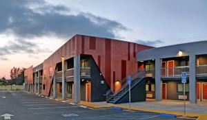 a red building with a staircase in a parking lot at Epic Hotel in Pico Rivera