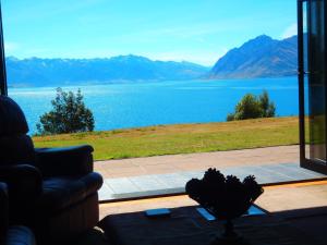 a living room with a view of the water at Lakefront Bellevue Lake Hawea Wanaka in Lake Hawea
