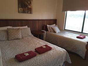 1 dormitorio con 2 camas y toallas rojas. en Cosy Corner Chalets, en Kronkup