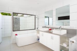 a white bathroom with two sinks and a bath tub at First Landing Beach Resort & Villas in Lautoka