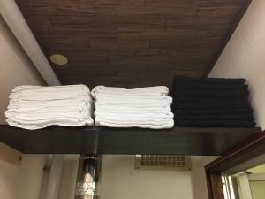 two stacks of white towels on a shelf in a room at Cool-Residence OTARU in Otaru