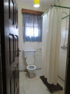 a bathroom with a toilet and a shower curtain at Bikeventures House Uganda in Jinja