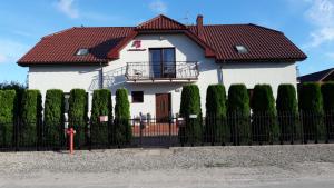 a white house with a red roof and a fence at Malinowe Lato in Grzybowo