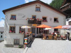 a white building with umbrellas and tables and chairs at Ferienwohnung Caviezel in Tschlin 