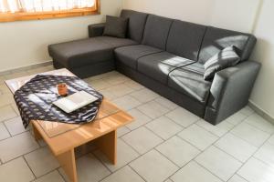 a living room with a black couch and a table at Studios Koukis in Kitriaí