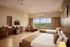 a hotel room with two beds and a large window at Athome Comforts in Panaji