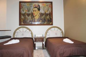 two beds in a room with a painting on the wall at Hotel El Refugio in Tlaxcala de Xicohténcatl