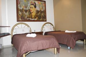 two beds in a room with a painting on the wall at Hotel El Refugio in Tlaxcala de Xicohténcatl