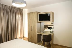 a bedroom with a bed and a desk with a television at Mervin Hotel in Krujë