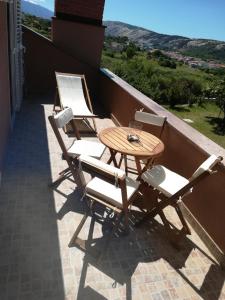 three chairs and a table on a balcony at Apartments Mestrovic in Lopar