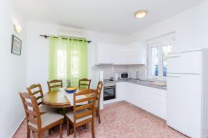a kitchen with a table and chairs and a kitchen with white cabinets at Classy Apartment Center in Split