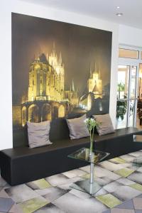 a black couch in a room with a castle mural at H+ Hotel Erfurt in Erfurt