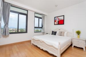 a white bedroom with a white bed and windows at The Ocean Apartment IDCWH B602 in Danang +15 photos