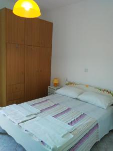 a bedroom with a bed with white sheets and a yellow light at Falopa Apartments in Parga