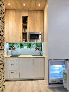 kuchnia z białymi szafkami i kuchenką mikrofalową w obiekcie Apartament Egzotyczny w Toruniu