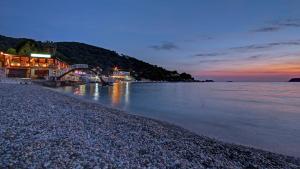 a beach with buildings and the water at night at Hotel Vis in Dubrovnik