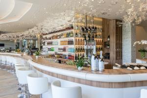 a bar in a restaurant with white chairs and wine bottles at Amadria Park Ivan in Šibenik