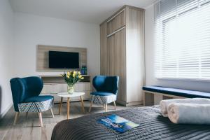 1 dormitorio con 2 sillas azules y TV en Green Village w Aquapark Reda, en Reda