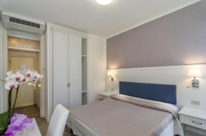 ein Schlafzimmer mit einem Bett und einer Vase aus Blumen in der Unterkunft Hotel Il Caravaggio in Marina di Pietrasanta