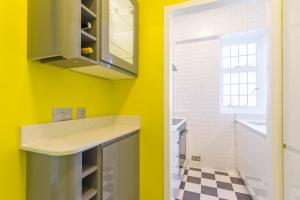 uma casa de banho com paredes amarelas e um lavatório em Chic 1 Bed Studio Flat in Popular Bloomsbury em Londres