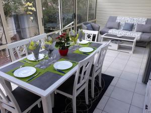 einen weißen Tisch mit Stühlen, Teller und Blumen auf der Veranda in der Unterkunft Gite au bord du Lac in Montville