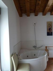 Casa Rural La Antigua Fragua في Los Llanos de Tormes: حوض استحمام أبيض في حمام ذو سقف خشبي