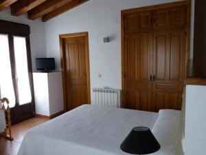 a bedroom with a white bed and wooden cabinets at Casa Rural La Antigua Fragua in Los Llanos de Tormes