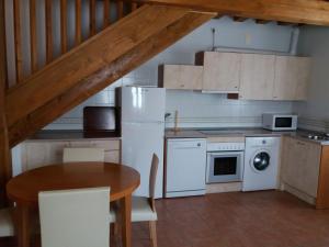 a kitchen with white appliances and a wooden table at Casa Rural La Antigua Fragua in Los Llanos de Tormes