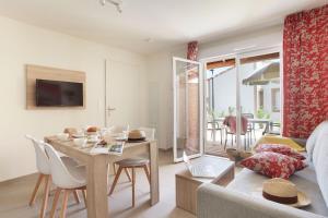 a living room with a couch and a table with chairs at Résidence Odalys Fleur de Sel in Aigues-Mortes