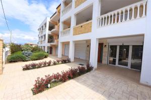 a white apartment building with flowers in a courtyard at Eleonas Apartments in Nea Moudania