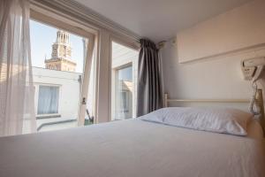a bedroom with a bed and a window with a clock tower at Travel Hotel Amsterdam in Amsterdam +27 photos