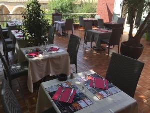 un restaurante con mesas y sillas con servilletas rojas en Hotel Aurelia, en Les Arcs sur Argens