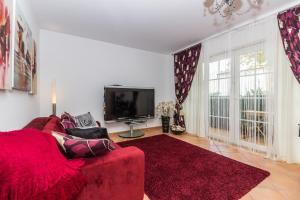 a living room with a red couch and a flat screen tv at Cabanas2stay in Cabanas de Tavira