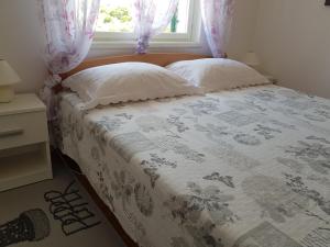 a bed with two pillows and a window at Apartmani Agard in Brodarica
