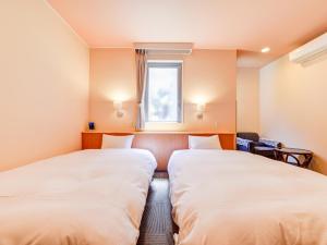 two beds in a room with a window at Hotel Belleforet in Tsushima
